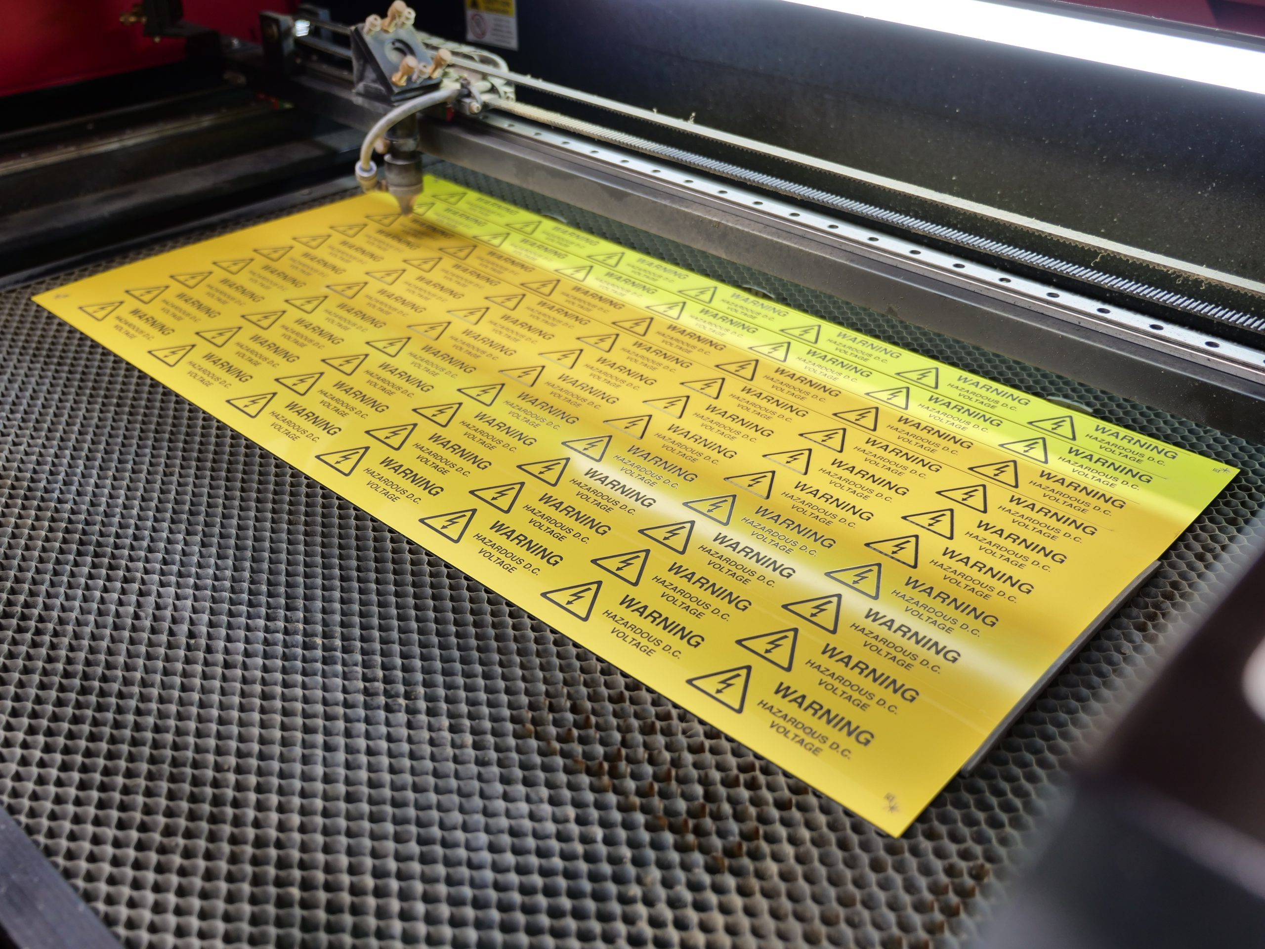 A laser cutter cutting out some yellow and black hazard labels